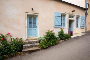 a house with blue doors and flowers in front of it at Les Demeures du Tonnelier, Maison Rue in Saint-Romain