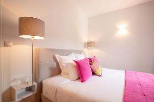 una camera da letto con un letto con cuscini rosa e bianchi di Les Demeures du Tonnelier, Maison Rue a Saint-Romain