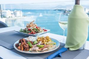 a table with two plates of food and a glass of wine at Hara Hotel in Chalkida