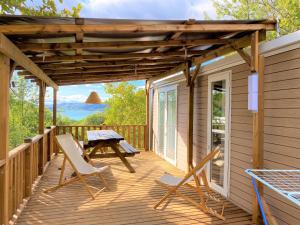 une terrasse en bois avec des chaises et une table de pique-nique. dans l'établissement Les Bastides de Chanteraine Hôtel de plein air & spa, à Aiguines