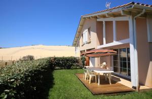 una casa con una mesa y una sombrilla en una cubierta en Résidence Belle Dune Blanche, maisons et appartements, en Biscarrosse-Plage
