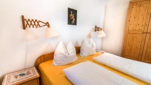 um quarto com uma cama com almofadas brancas em Residence Lärchenhäusl em Soprabolzano