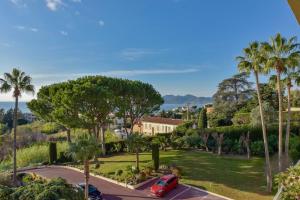 uma vista para um parque com palmeiras e um carro vermelho em SERRENDY ROOFTOP TERRACE in residential property WITH POOL & SEA VIEW ! em Cannes