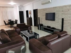 uma sala de estar com sofás e uma televisão de ecrã plano em Residence Galaxy Togo em Lomé