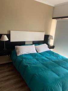 1 dormitorio con 1 cama azul grande y 2 almohadas en Departamento Aristobulo en Mar del Plata
