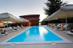 a large swimming pool with chairs and umbrellas at Pension Riviera-Šilo in Šilo