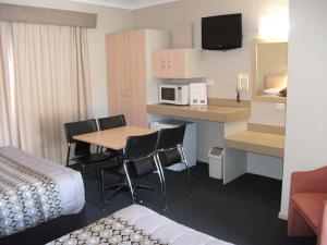 a hotel room with a kitchen and a table and chairs at Baybrook Motor Inn in Muswellbrook