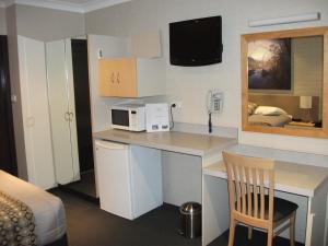 a kitchen with a refrigerator, microwave, sink and dishwasher at Baybrook Motor Inn in Muswellbrook