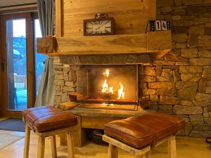 a fireplace with a stone wall with a clock and stool at Chalet Beaufort in Saint-Martin-de-Belleville