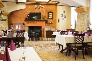 a dining room with tables and chairs and a fireplace at Vadász Panzió és Étterem in Szombathely