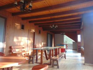 uma sala de jantar com mesas e bancos e tectos em madeira em Cabaña dentro del Bosque para 24 Personas em Mazamitla