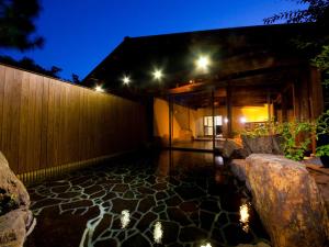 un patio con suelo de piedra y luces por la noche en Hatago Kounokura, en Yufu