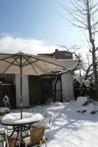une table et des chaises avec un parasol dans la neige dans l'établissement K's House MtFuji -ケイズハウスMt富士- Travelers Hostel- Lake Kawaguchiko, à Fujikawaguchiko