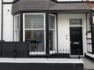 a house with a black door and a window at Sandleigh Apartment in Scarborough