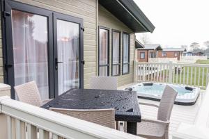 a deck with a table and chairs and a hot tub at The White Rose Lodge with Hot Tub in York