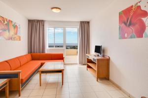 - un salon avec un canapé orange et une fenêtre dans l'établissement Apartments Palm Garden, à Morro del Jable