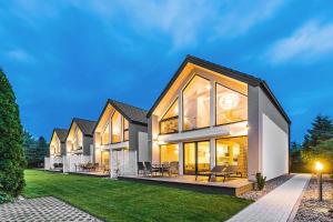 ein Haus mit beleuchteter Fassade in der Abenddämmerung in der Unterkunft Housea Domy Wakacyjne in Jantar