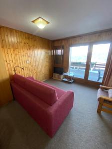 ein Wohnzimmer mit einem roten Sofa und einem Fenster in der Unterkunft Studios Bellevue 1 et 2, ski lift 150m in Veysonnaz