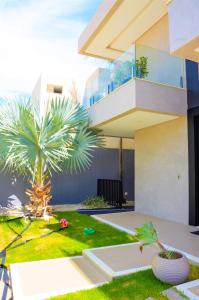 a house with a palm tree in front of it at Casa de Luxo na Praia - Sun Luxury Home in Aracaju