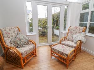 2 sillas de mimbre sentadas en una habitación con ventanas en Sea Peeps, en Paignton