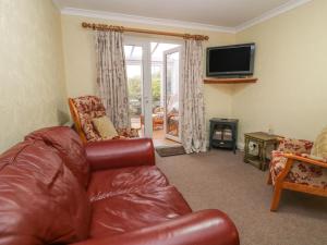 a living room with a leather couch and a television at Sea Peeps in Paignton