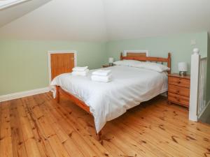 a bedroom with a bed with white sheets and a wooden floor at Sea Peeps in Paignton