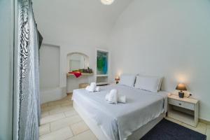 um quarto com uma grande cama branca com lençóis brancos em Casa Maritina private residence em Fira