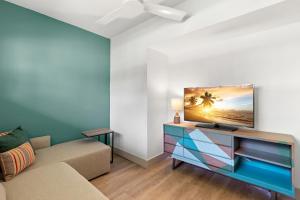 uma sala de estar com um sofá e uma televisão de ecrã plano em The Beachcomber St. Pete Beach Resort & Hotel em St. Pete Beach