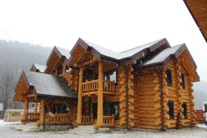 a log cabin with snow on the roof at Зимова казка in Tatariv