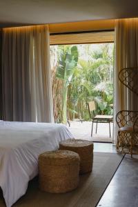 a bedroom with a bed and a large window with a chair at Makena Hotel in Icaraí