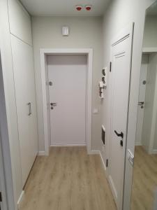 um corredor com paredes brancas e uma porta branca em Prestige Apartments em Rivne