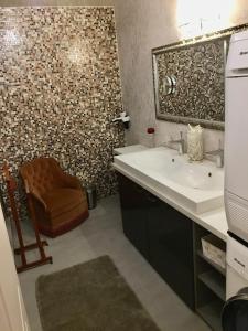 a bathroom with a sink and a mirror and a chair at Les 3 Coeurs - Chambres chez charmants habitants in Font