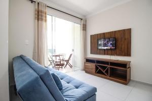 sala de estar con sofá azul y TV en Aluguel Apartamento 2 quartos s/ 1 suíte Bombas/SC, en Bombinhas