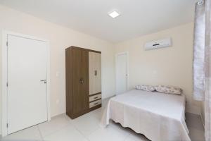 1 dormitorio con 1 cama y armario de madera en Aluguel Apartamento 2 quartos s/ 1 suíte Bombas/SC, en Bombinhas