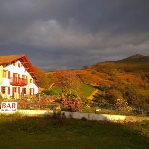 una casa blanca con una colina en el fondo en Maison Hordago Chambres d'hôtes, en Sare