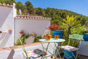 a table and chairs on a balcony with flowers at La Casita de las Mariposas in Frigiliana