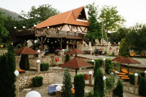 a large building with a deck in a garden at Hotel Etno Centar Balasevic in Boljevac