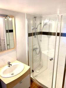 uma casa de banho branca com um chuveiro e um lavatório. em Gite "Au coeur de Riquewihr - vue sur le vignoble" à Riquewihr em Riquewihr