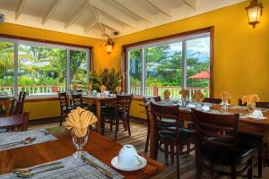 um restaurante com mesas e cadeiras de madeira e janelas em Rosalie Bay Eco Resort & Spa em Rosalie