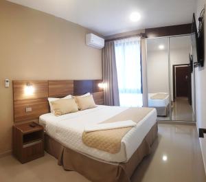 a bedroom with a large bed and a mirror at Premium Suites Deluxe Aparthotel Equipetrol in Santa Cruz de la Sierra