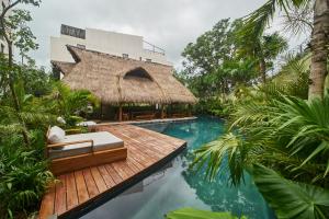 un complejo con piscina y un edificio con techo de paja en Modern Jungle Hideaway with Private Pool in Aldea Zama, en Tulum