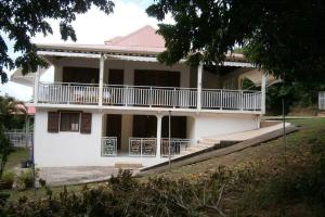a white house with a balcony on it at Au Soleil Couchant in Bouillante