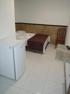 a small room with a bed and a refrigerator at Pousada Solar da Praia in Guarapari