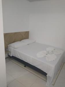 a bed with white sheets and towels on it at Pousada Solar da Praia in Guarapari