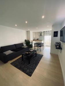ein Wohnzimmer mit einem schwarzen Sofa und einem Tisch in der Unterkunft Appartement les Falaises in Cap d'Agde