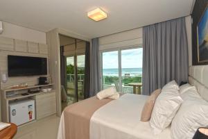 a hotel room with a bed and a large window at Hospedaria Home Suites Mariscal in Bombinhas