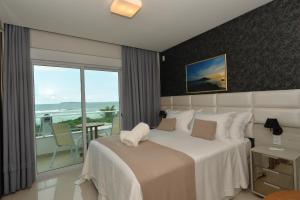 a bedroom with a bed with a view of the ocean at Hospedaria Home Suites Mariscal in Bombinhas