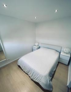 ein weißes Schlafzimmer mit einem Bett und zwei Nachttischen in der Unterkunft Appartement les Falaises in Cap d'Agde