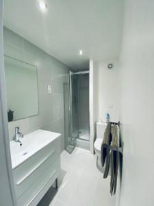 ein weißes Bad mit einem Waschbecken und einer Dusche in der Unterkunft Appartement les Falaises in Cap d'Agde