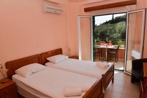 una camera con 2 letti e un balcone con tavolo di Paradise Apartments a Paleokastritsa